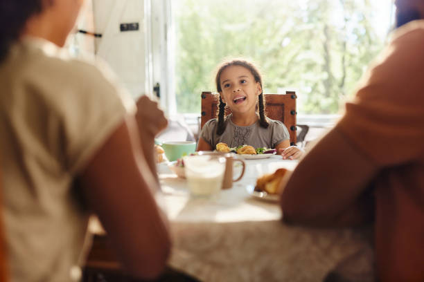 istock Happy black girl talking to her parents during breakfast at dining table. 2060120419