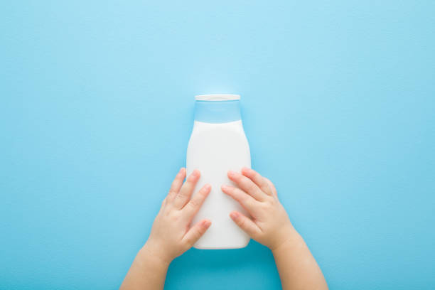 istock Baby boy hands holding white plastic bottle on light blue table background. Pastel color. Care about clean and soft body skin. Children beauty product. Closeup. Point of view shot. Top down view. 2060134770