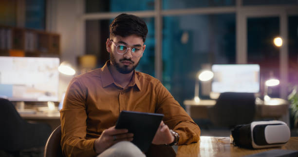 Businessman, reading or tablet for developer at work, tech or professional career in technology. Indian entrepreneur, plan or touchscreen for online research, vr or connection in start up company