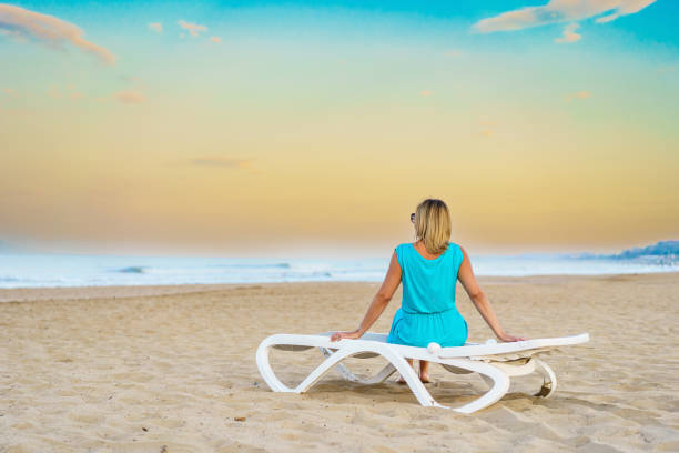 Woman sitting on sunbed relaxing on beach