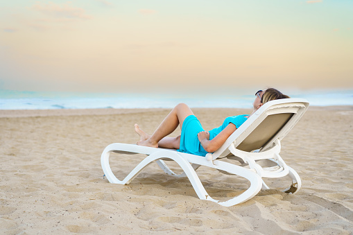 Full length photo of positive man dressed print shirt lay on deckchair at resort arms behind head isolated on purple color background.