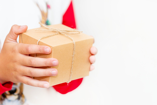 Young boy hands in pullover holding Christmas gift box on gray background.Christmas and New Year banner.Copy space.