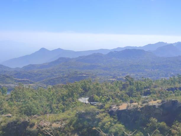 Clear view of blue sky, white clouds, mountains from the highest point of Mount Abu which is Guru Shikhar. A view of small villages from the the top