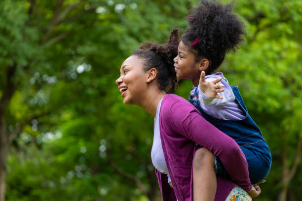 istock African American mother is playing piggyback riding with her young daughter while having a summer picnic in the public park for wellbeing and happiness 2060154441