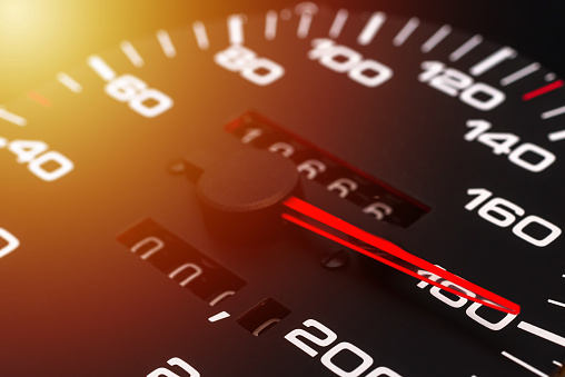 Car speedometer. Auto car speedometer shows 180 km h or miles.Closeup shot,dark black background.Automobile dangerous speed concept