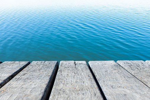 Blue Water Calm Waves Surface as Old wooden tables Background.Calm water surface with small ripples.Nice blue water background.Copy space.