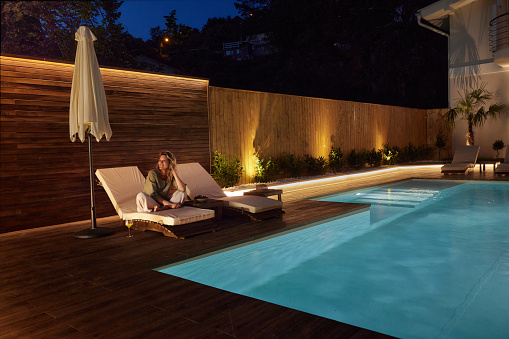 A backyard swimming pool and Hot Tub hot tob at night with solar lights around the fence for privacy and illumination.