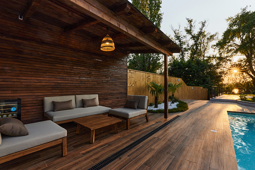 Cozy patio with furniture in the backyard of a house by the swimming pool.