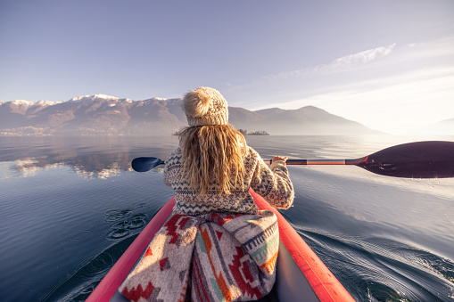 Weekend activity, woman in a red canoe on a calm lake surrounded by mountains