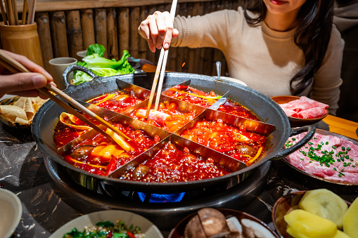 Female tourist eating original mala spicy hot pot in Chongqing, China