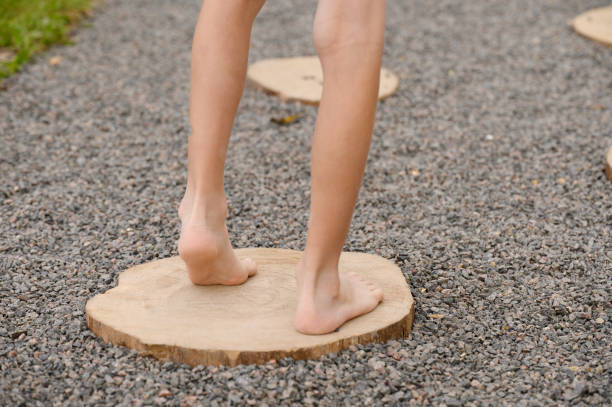 Path of health. The child walks along a sensory path with different surfaces, walks barefoot on stumps and small stones. Touch massage track for feet. Prevention of flat feet