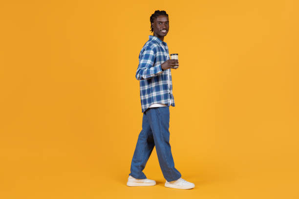 istock Relaxed young black man walking with takeaway coffee cup in hand 2060222501