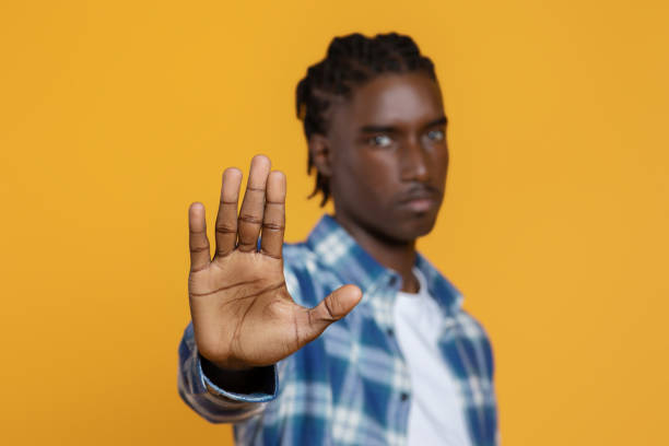 istock Young black man gesturing STOP with open palm on yellow studio background 2060223067