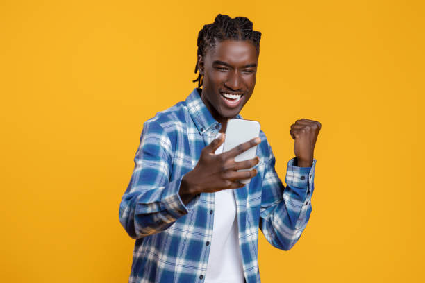 istock Cheerful excited young black man with smartphone celebrating success 2060223413