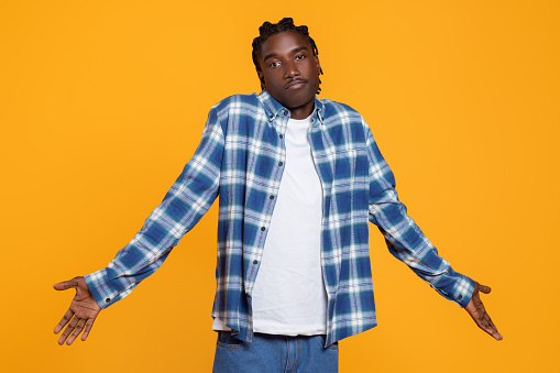 I Don't Know. Puzzled Black Guy Shrugging Shoulders And Looking At Camera, Hesitant Unsure African American Man Having No Answer, Standing Isolated On Yellow Studio Background, Copy Space