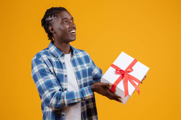 istock Delighted young black man holding white gift box with red ribbon 2060223654