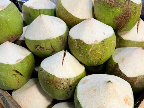 Stock photo showing close-up view of fresh fruit produce, immature coconuts displayed at market on a street food market stall.