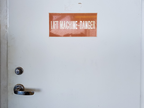 Lift machine danger sign on the door of a machine room.