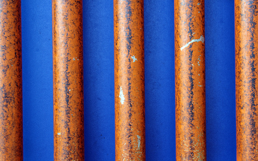 Vertical orange-brown metal bars against a blue background texture abstract