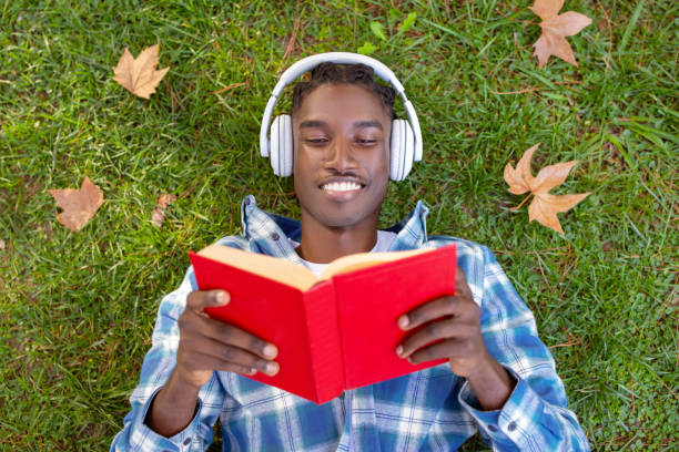 istock Contented black man on grass engrossed in book outside 2060249248