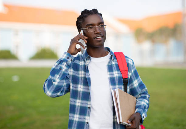 istock Smiling African Student Guy Talks On Cellphone While Walking Outdoors 2060249294