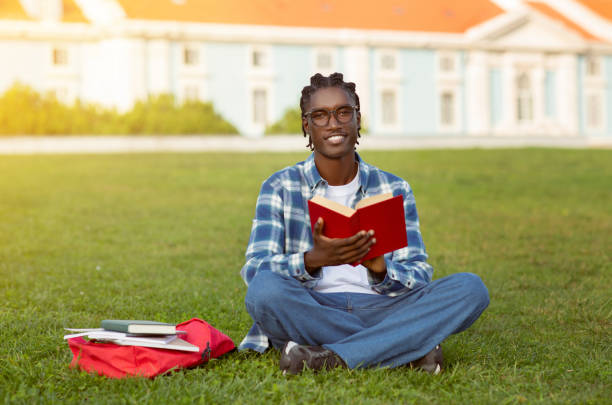 istock Black Student Guy Learning Reading Book Sitting Outdoors Of University 2060250498