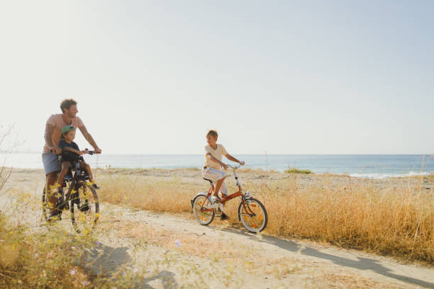 Father and his two boys exploring the coastline on a bicycle