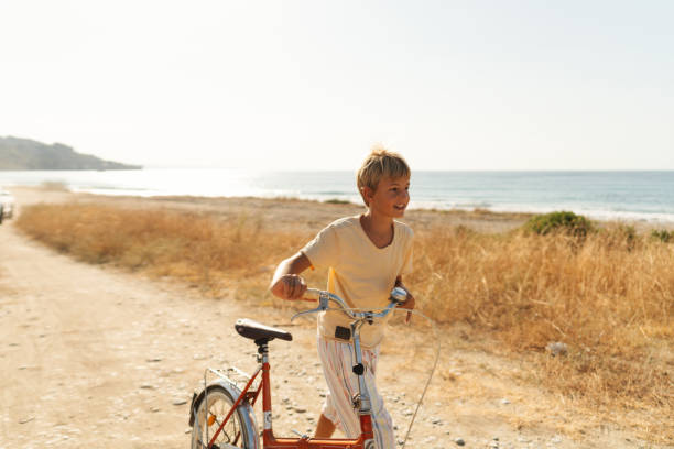 Photo of a young boy riding a bicycle and exploring the coastline