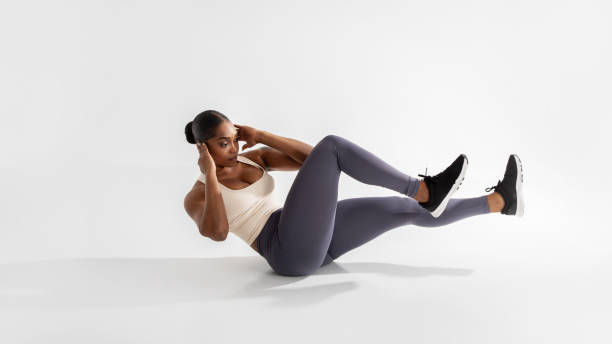 istock Athletic african american woman does elbow to knee crunches, studio 2060260485