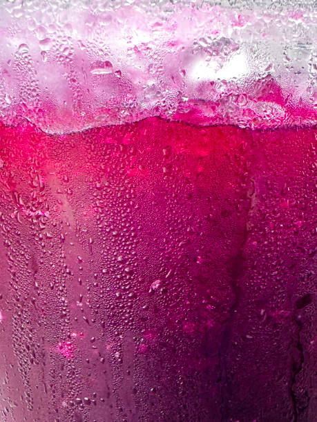 image plein cadre d’une cruche en verre recouverte de condensation avec une boisson violette de jus de cassis, de glaçons et de neige fondue de glace pilée, mise au point au premier plan - crushed ice colors grape fruit photos et images de collection