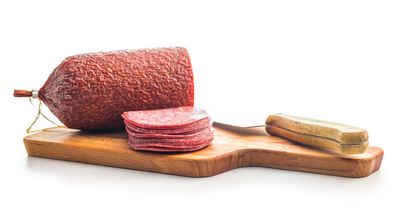 Sliced salami sausage on cutting board isolated on the white background.