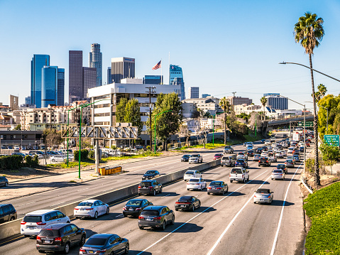 The Santa Ana Freeway busy with traffic, with the skyscrapers of Downtown LA on the horizon.