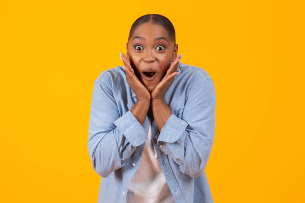istock black lady shouting in excitement touching face over yellow background 2060277880