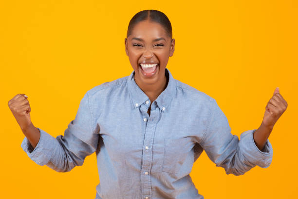 istock black lady screaming with joy shaking fists over yellow background 2060277882