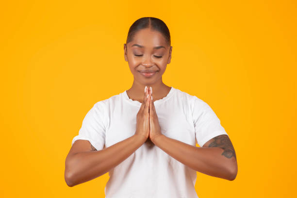 istock Black Woman Praying Holding Clasped Hands On Yellow Studio Background 2060278265
