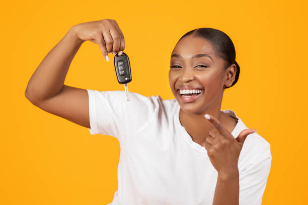 Excited Black Woman Showing Key Celebrating Buying Auto, Yellow Background New Car. Excited Black Woman Showing Key In Excitement Celebrating Buying New Auto On Yellow Studio Background, Smiling To Camera. Dreams Come True, Own Vehicle Purchase Concept car key stock pictures, royalty-free photos & images