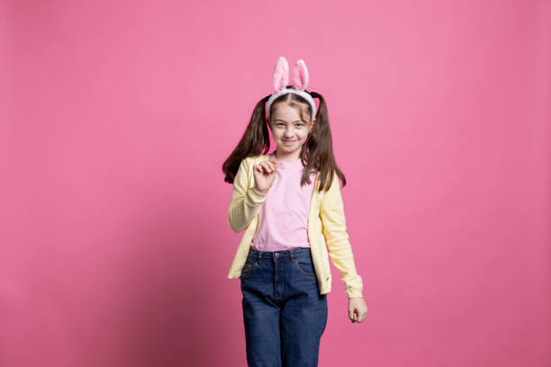 istock Positive small kid with pigtails and fluffy bunny ears fooling around in studio 2060287239