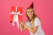 blonde lady in party hat posing with gift box, studio