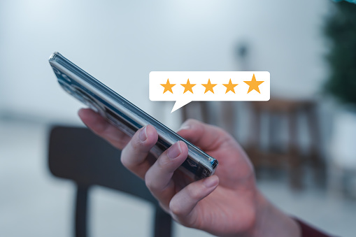 Customer satisfaction survey and feedback rating concept. The client is using a mobile smartphone to give a 5-star satisfaction score for an excellent experience. Online feedback and review service.