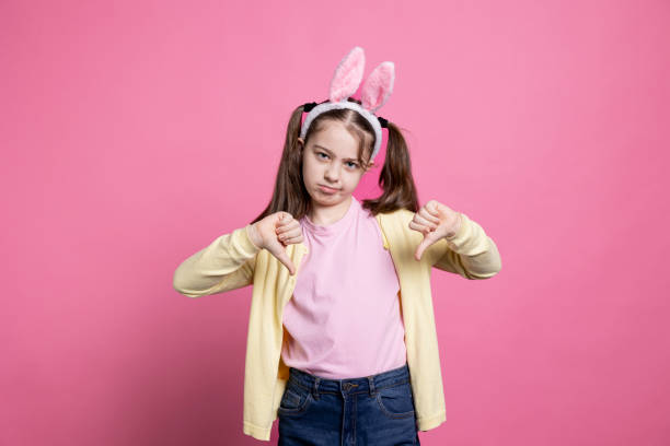 istock Negative displeased young kid showing thumbs down sign in studio 2060292885