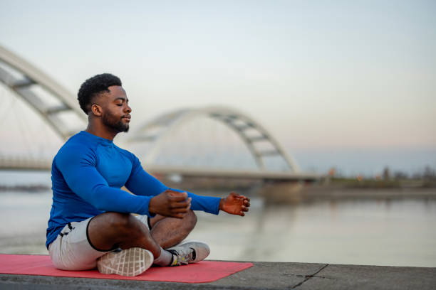 Young black man wearing athletic wear sitting and exercising yoga