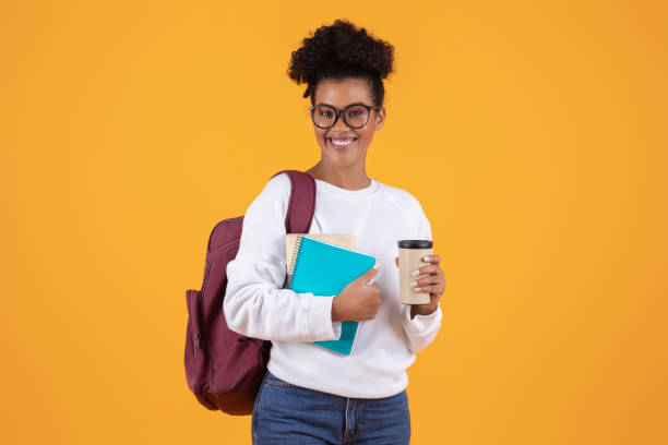 istock Black female student wearing glasses and backpack holding notebooks and takeaway coffee 2060297941