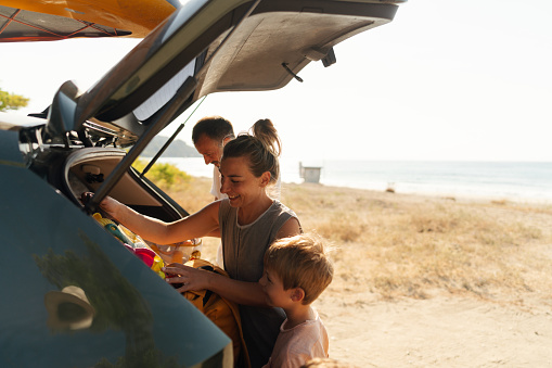 Photo of an adventurous family with two young boys, on a summer road-trip with a family car,  found a perfect local beach to spend a hot summer day