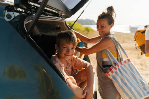 Unpacking my precious belongings from a car-trunk Photo of an adventurous family with two young boys, on a summer road-trip with a family car, going to the local beach on a hot summer day family beach vacations travel stock pictures, royalty-free photos & images