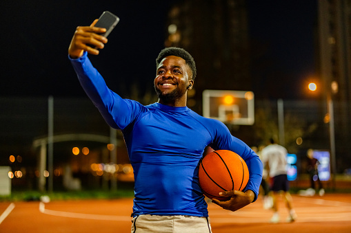 African American man captures a moment of his night on the basketball court with a selfie.