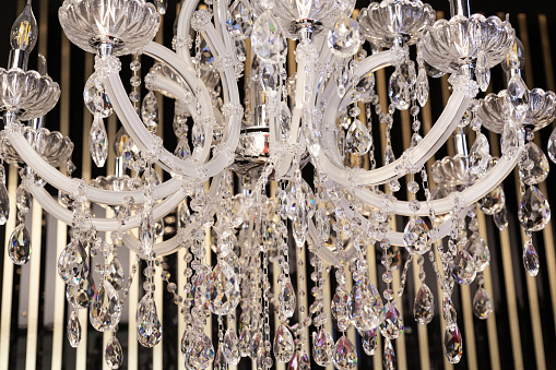 A white crystal chandelier hangs from the ceiling, close-up.