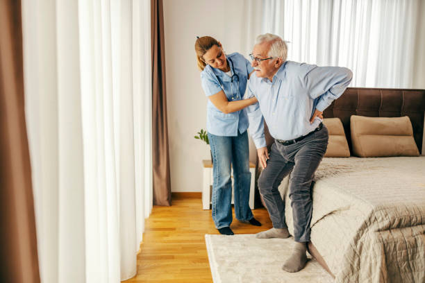 istock A nurse is helping a senior man to get up from bed. 2060369826