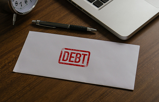 Debt concept. Debt word in paper envelope at workplace in office. financial obligation, loan payment, heavy load of money failure, inflation, mortgage or borrowing money problem.