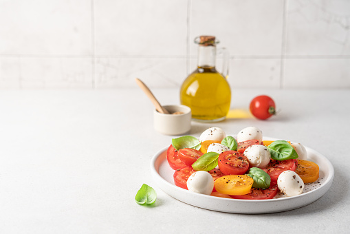 Tomatoes mozzarella basil salad close-up view on white background