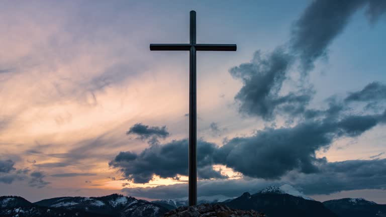 Clouds moving fast over religious steel cross in peaceful nature, christian symbol of religion and faith heaven time lapse